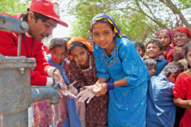 Ein Mitarbeiter klärt Schülerinnen und Schüler über die richtige Handhygiene auf.